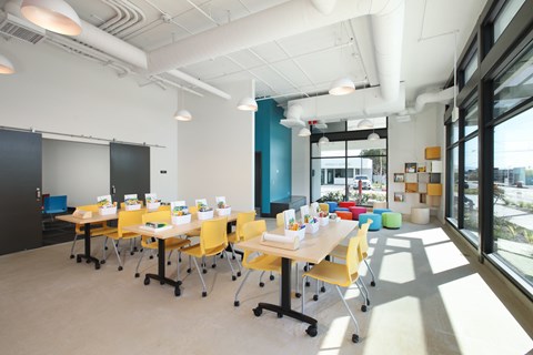 A conference room with yellow chairs and white tables.