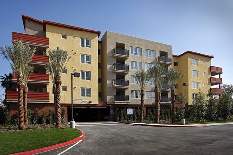 A large apartment complex with a red roof and palm trees in front.