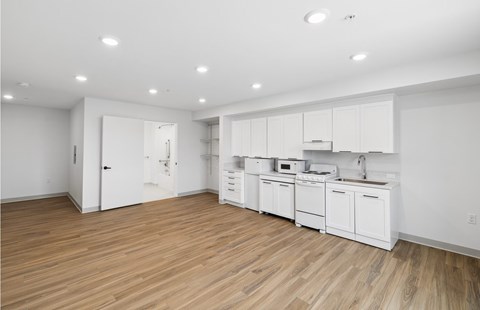 A kitchen with white cabinets and wooden floors.