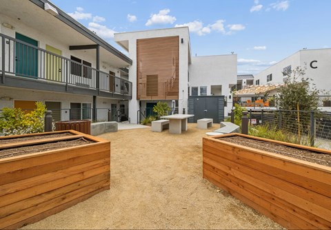 A courtyard with a wooden fence and a white building in the background.