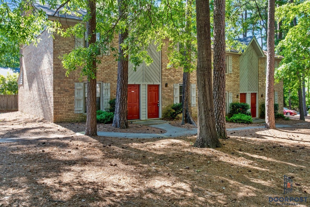 a brick house with a red door and trees