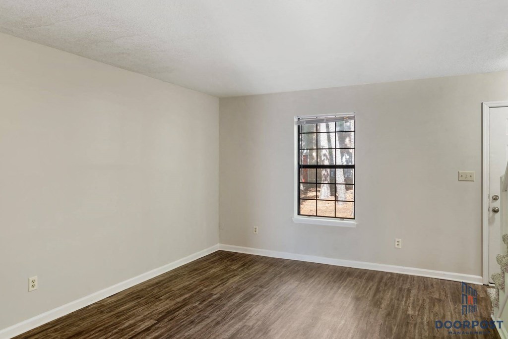 an empty living room with wood floors and a window