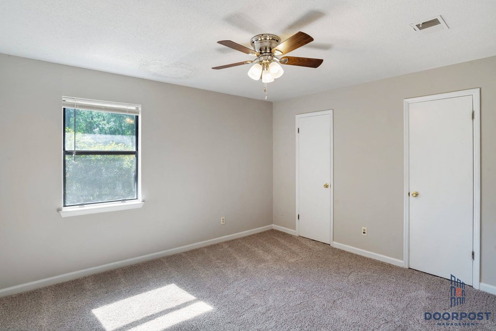 an empty living room with a ceiling fan and a window