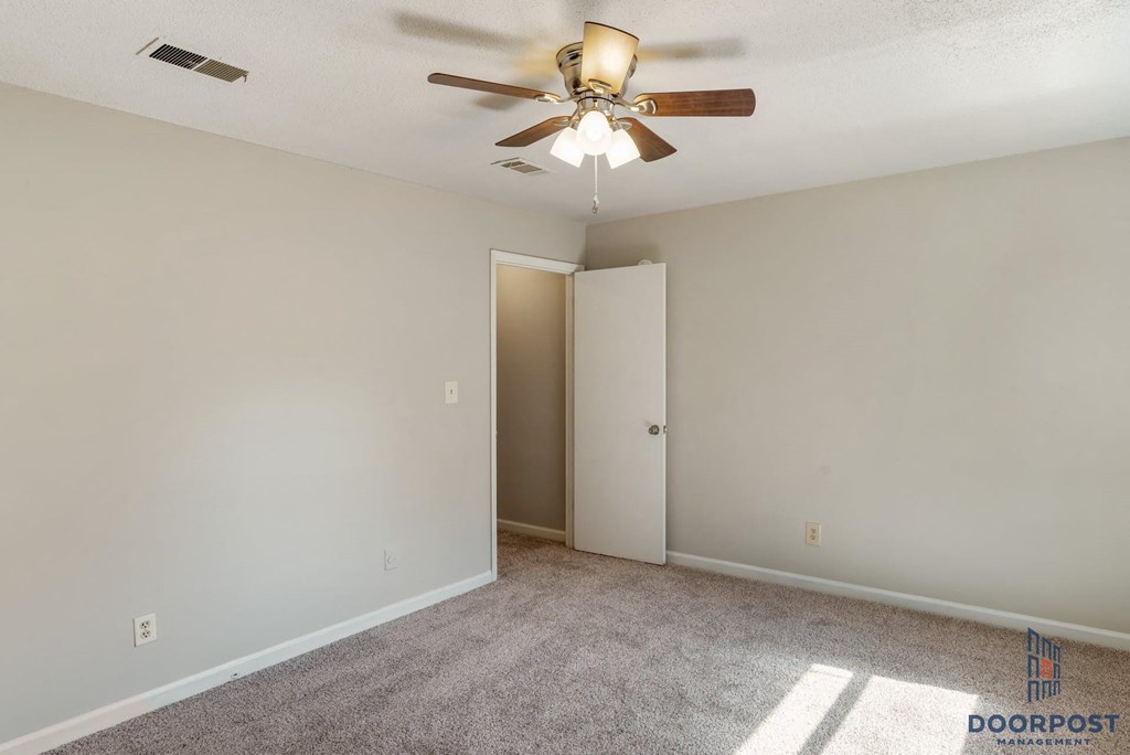 an empty living room with a ceiling fan and a door to a closet