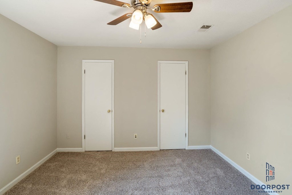 a empty room with a ceiling fan and two doors