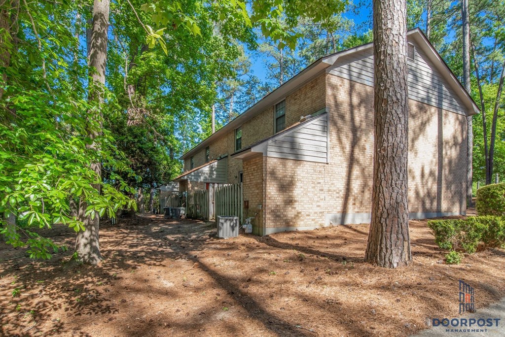a house in the woods with a driveway and trees