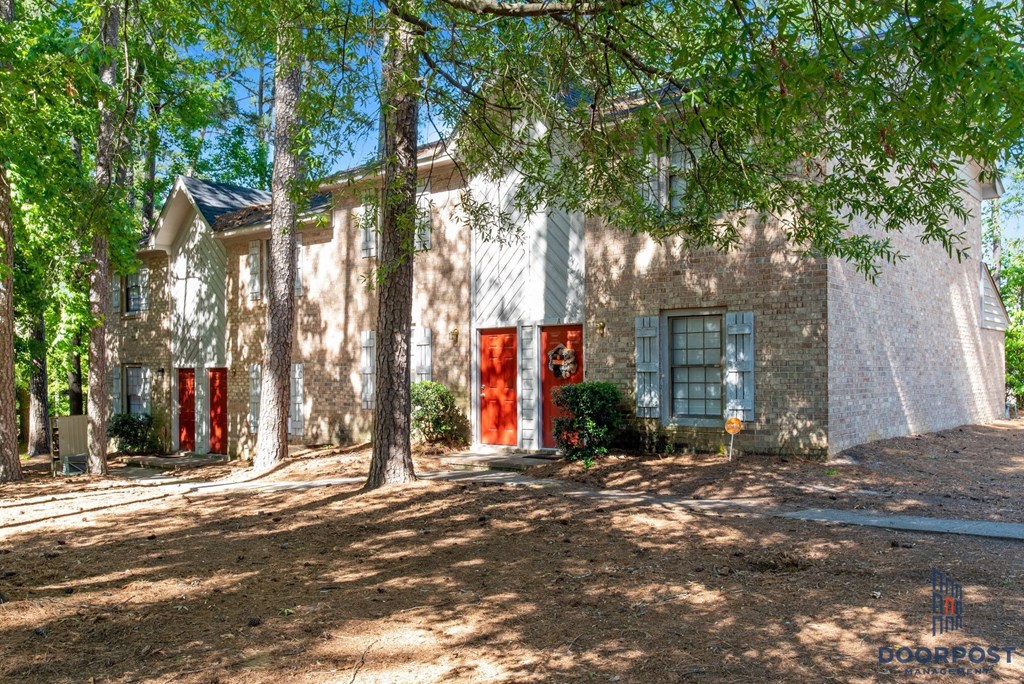 a house with red doors and trees in front of it