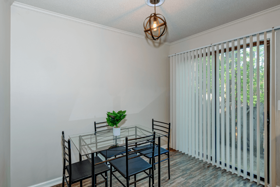 a dining room with a glass table and chairs and a window with blinds
