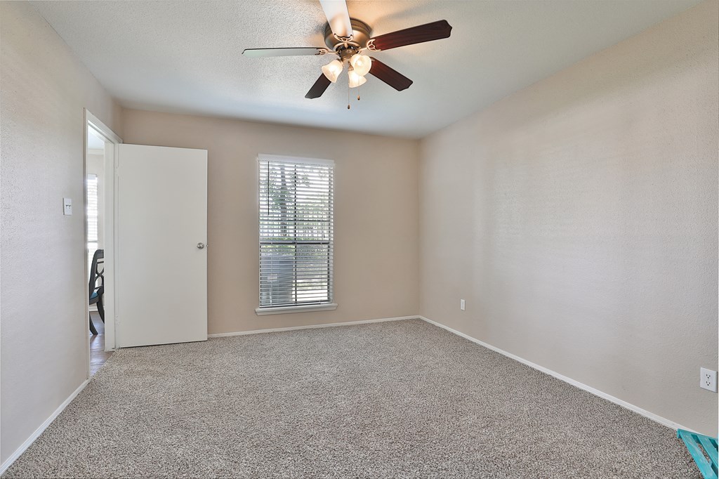 an empty living room with a ceiling fan and a closet