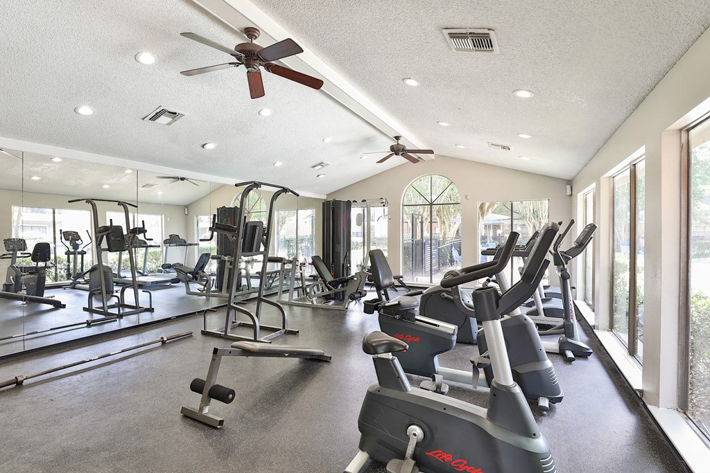 a gym with cardio machines and ceiling fans