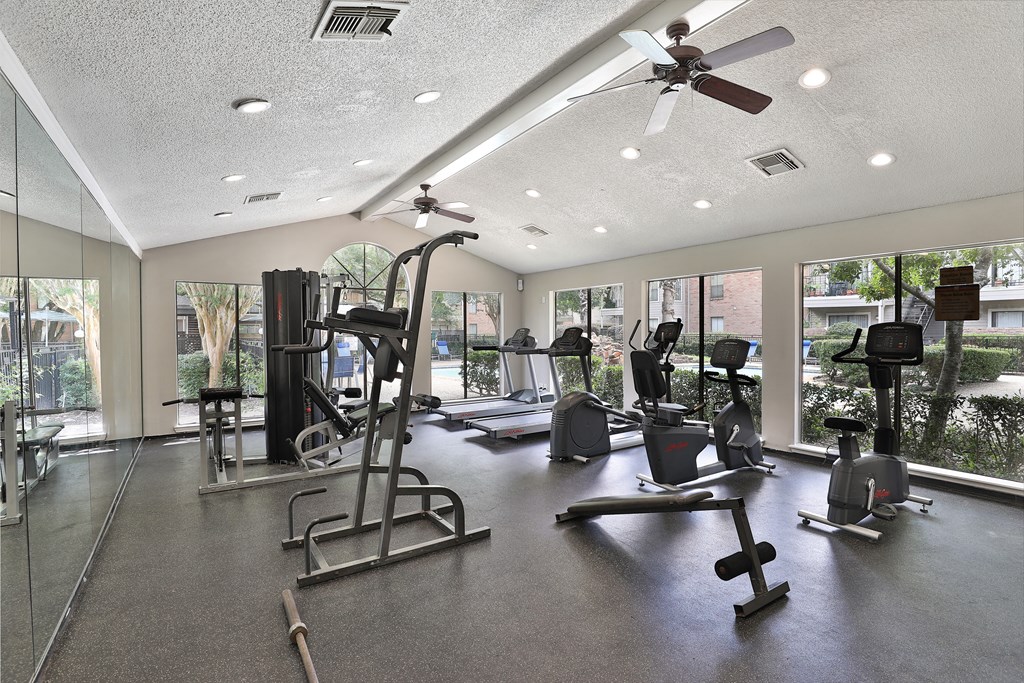 a gym with cardio machines and a ceiling fan