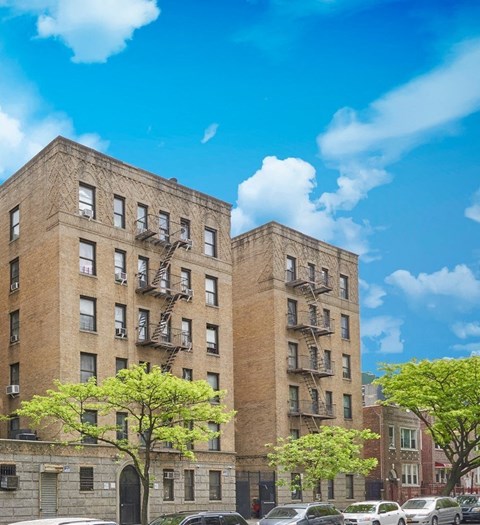Two brown buildings with fire escapes on the side.
