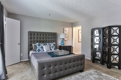 A bedroom with a large bed and a grey tufted headboard.
