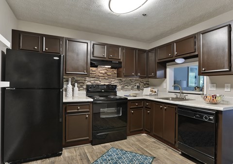 A kitchen with black appliances and brown cabinets.