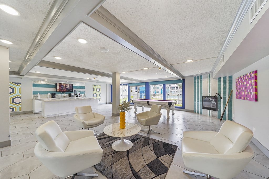 a living room with white chairs and a pool table