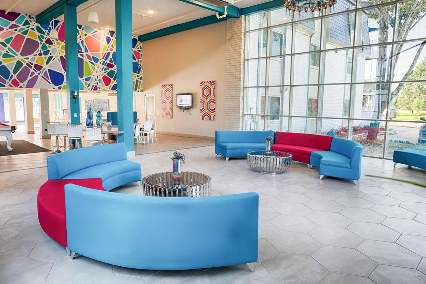 a lobby with blue couches and chairs and large windows
