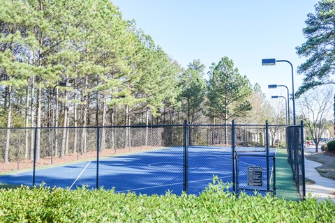 A tennis court surrounded by a fence and trees.