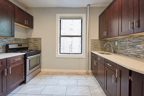 A kitchen with dark wood cabinets and a stone backsplash.