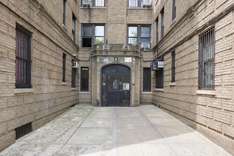 A courtyard surrounded by brick buildings with a black door in the middle.