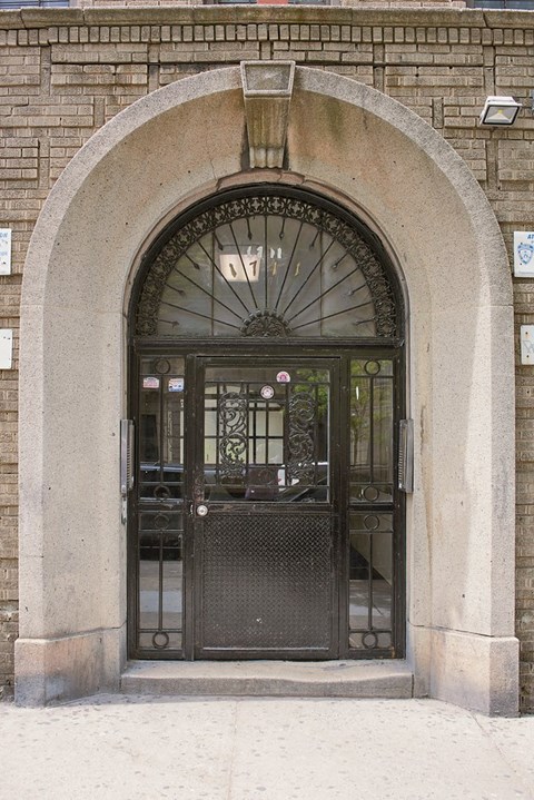 A black wrought iron gate is set in a stone archway.