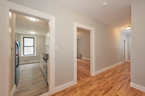 A kitchen with a refrigerator, sink, and oven is visible through an open door.
