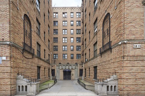 A brick building with a gate in the middle of a courtyard.