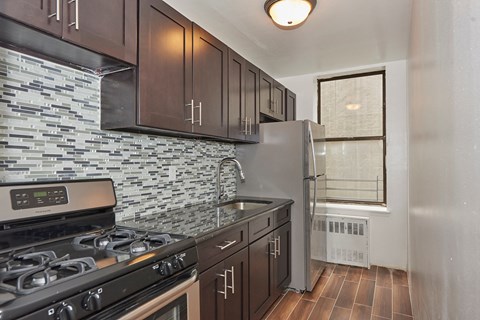 A kitchen with a stove, refrigerator, and cabinets.
