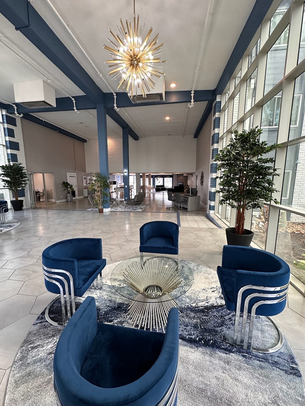 a large lobby with blue chairs and a glass table