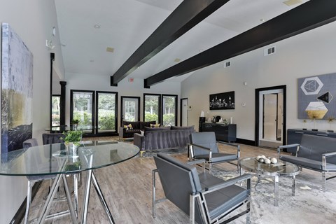 A modern living room with a glass table and grey chairs.