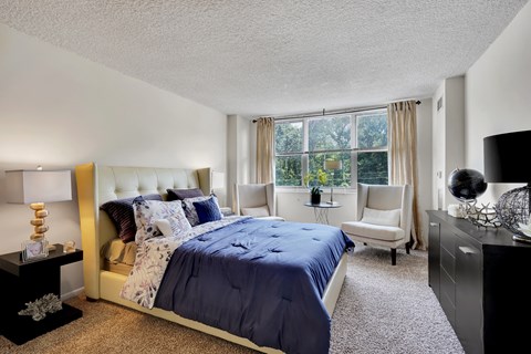 A bedroom with a large bed and a window with curtains.