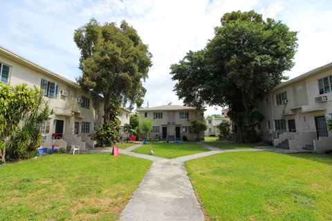 A grassy area with a concrete walkway separates two rows of houses.