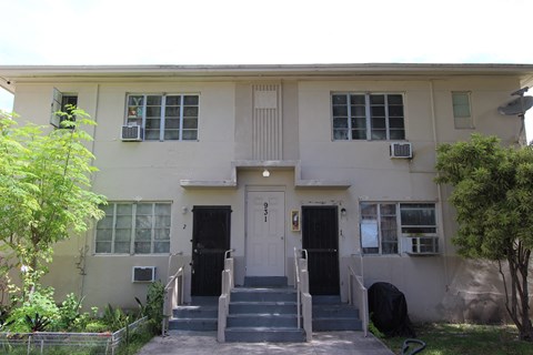 A two-story building with a black front door and steps leading up to it.
