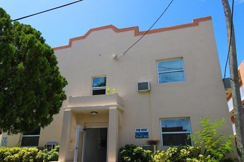 A two-story building with a "For Rent" sign in front.