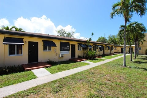 a row of yellow houses with palm trees in the background