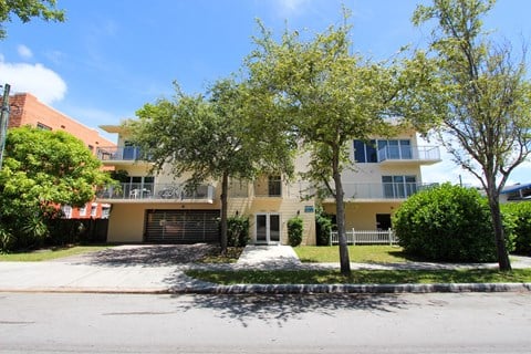 a large yellow and white apartment complex with trees in front of it