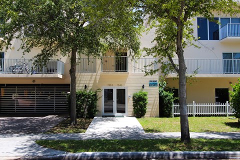 A building with a white fence and a tree in front of it.