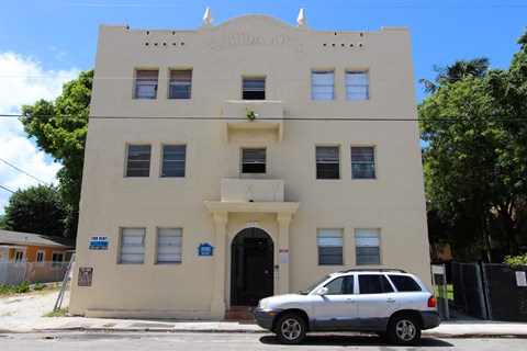 a white car parked in front of a white building