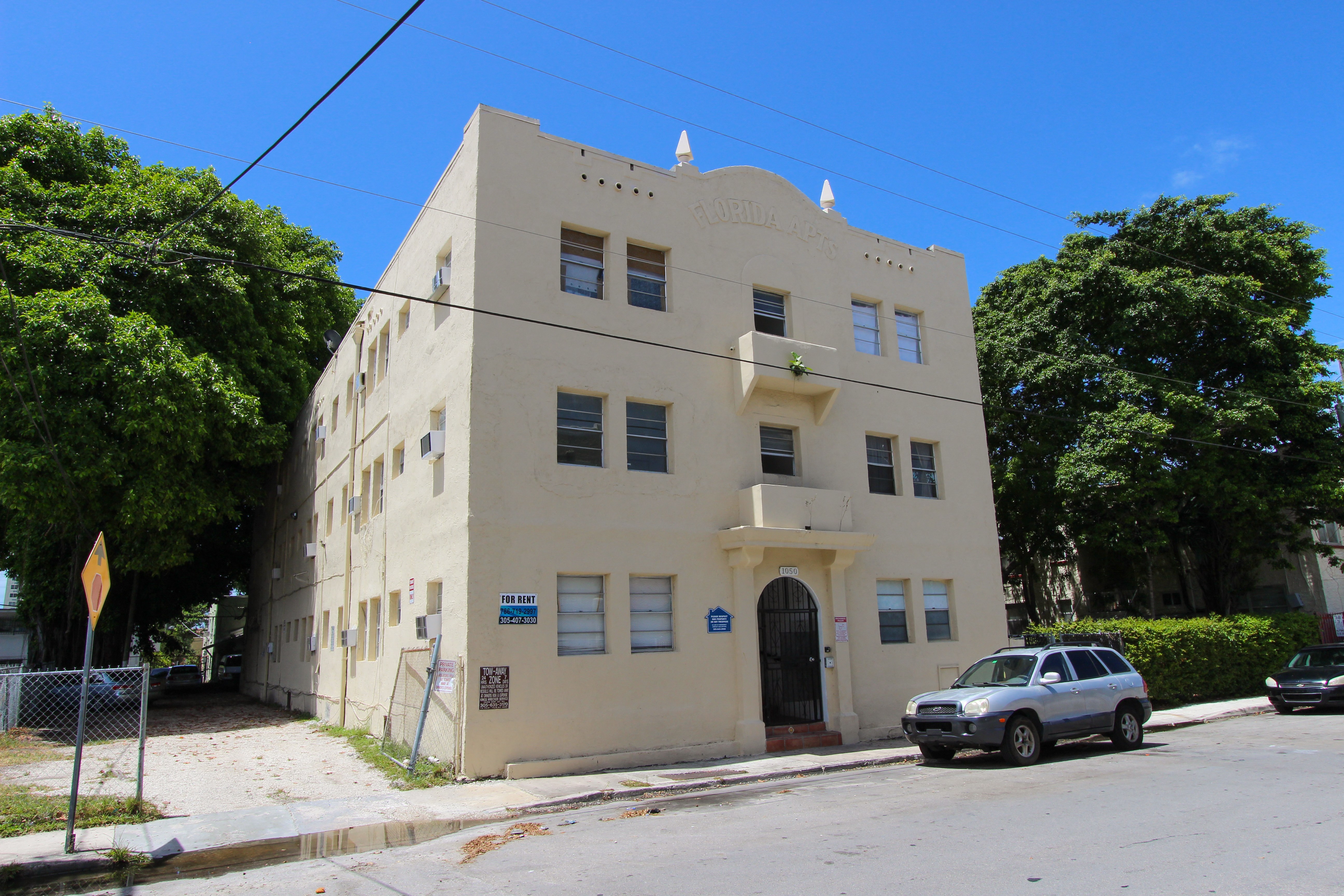 a building on the corner of a street with a car parked in front of it