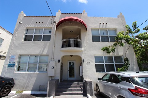 A two-story building with a balcony on the second floor is for rent.