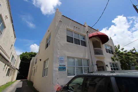 a white building with an awning and a car parked in front of it