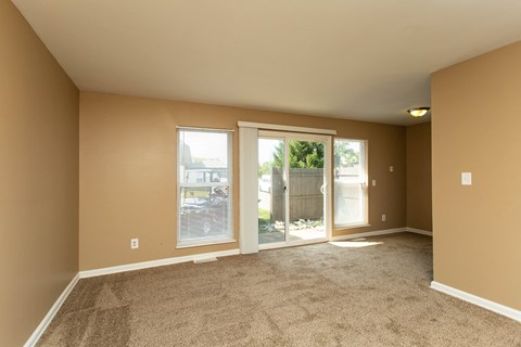 A room with carpeted floor and sliding glass doors.