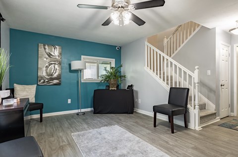 A living room with a staircase and a ceiling fan.