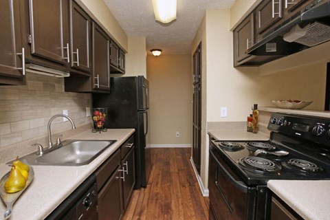 A kitchen with black appliances and brown cabinets.