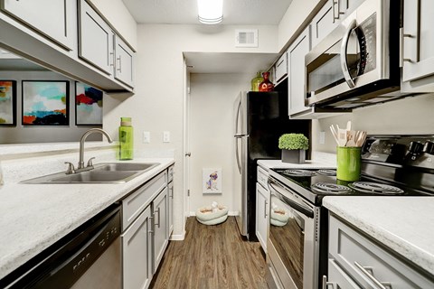 an updated kitchen with white cabinets and stainless steel appliances