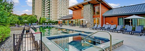 A large outdoor swimming pool with a hot tub in the middle of it.