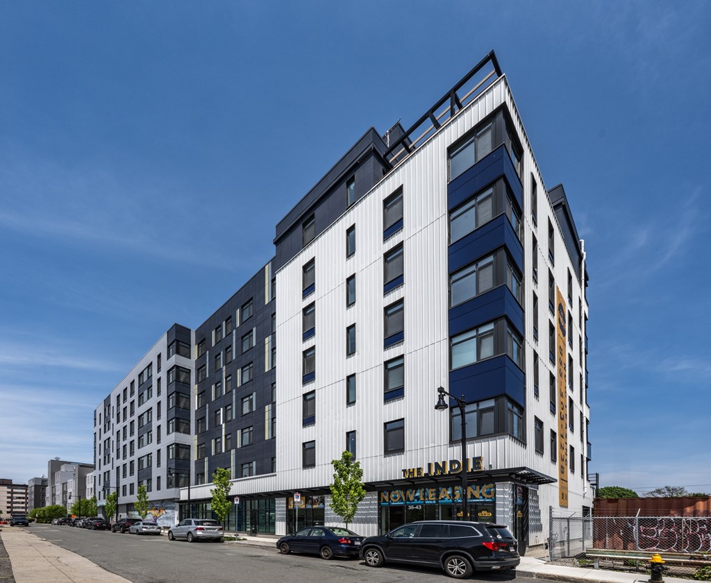 A modern multi-story building with a black car parked in front.