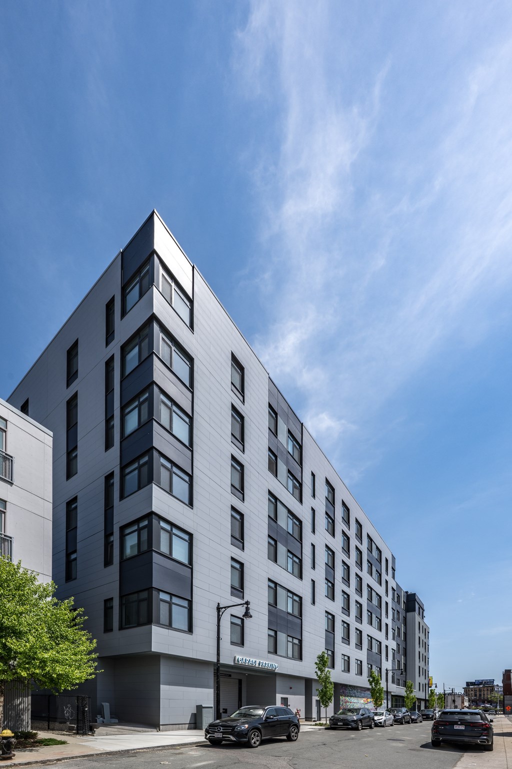 A modern building with a grey facade and a parking lot in front.