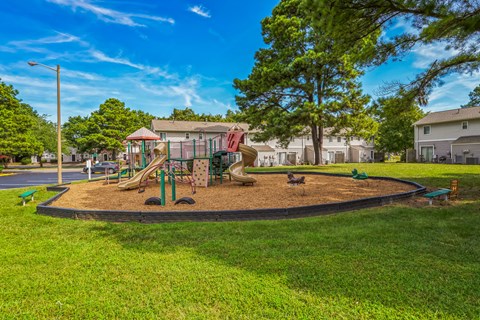 A playground with a slide and swings in a park.
