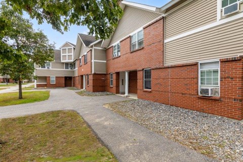 a brick apartment building with a paved walkway