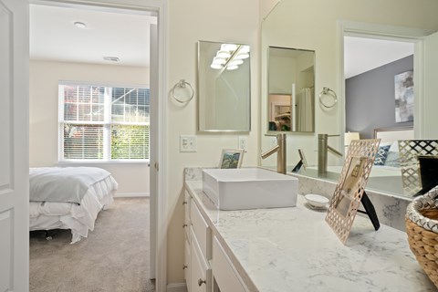A white bedroom with a large mirror and a white bed.